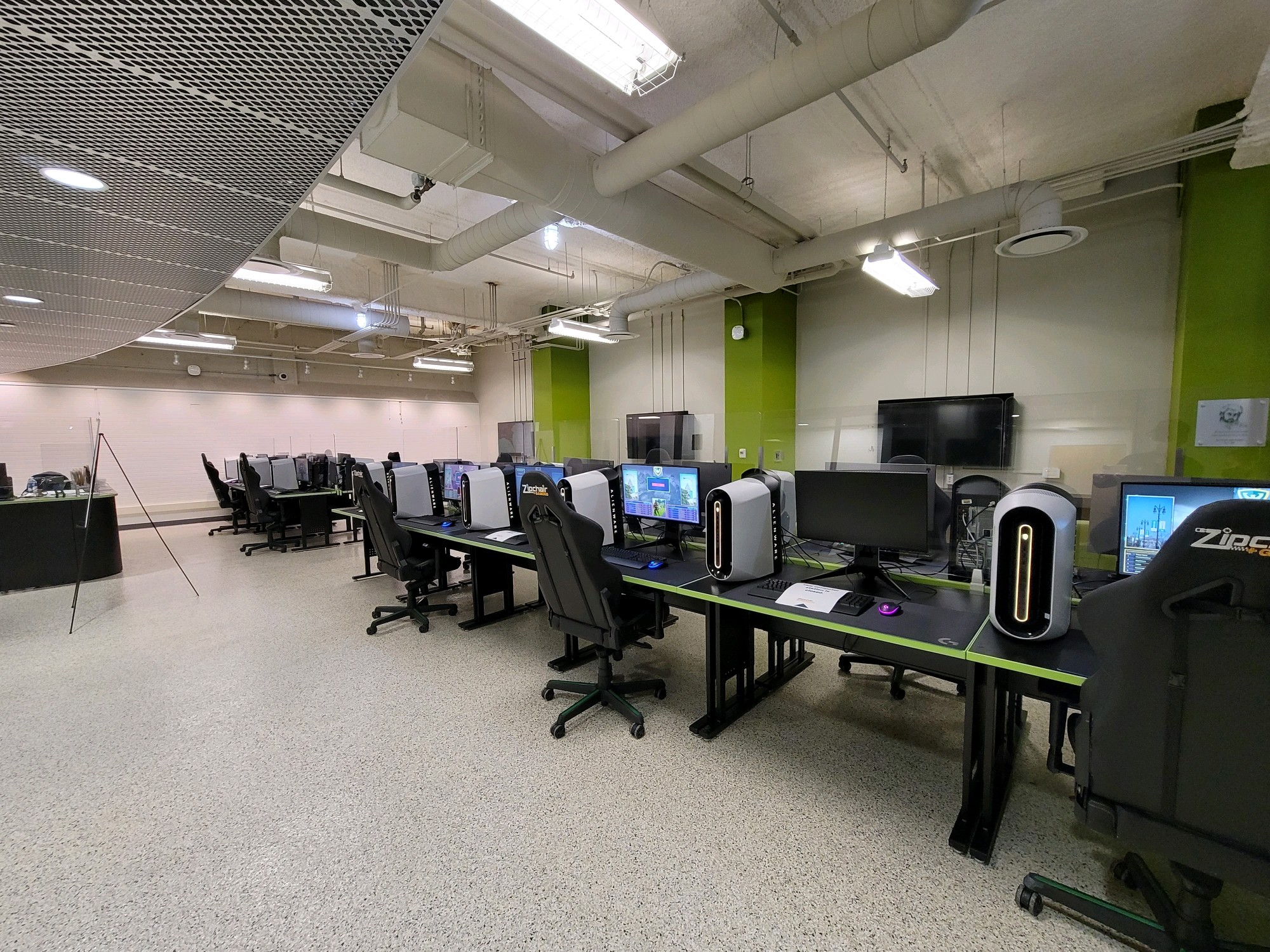 Image of the esports facility showing multiple workstations with computers, a staff desk area and BYOD tv stations.